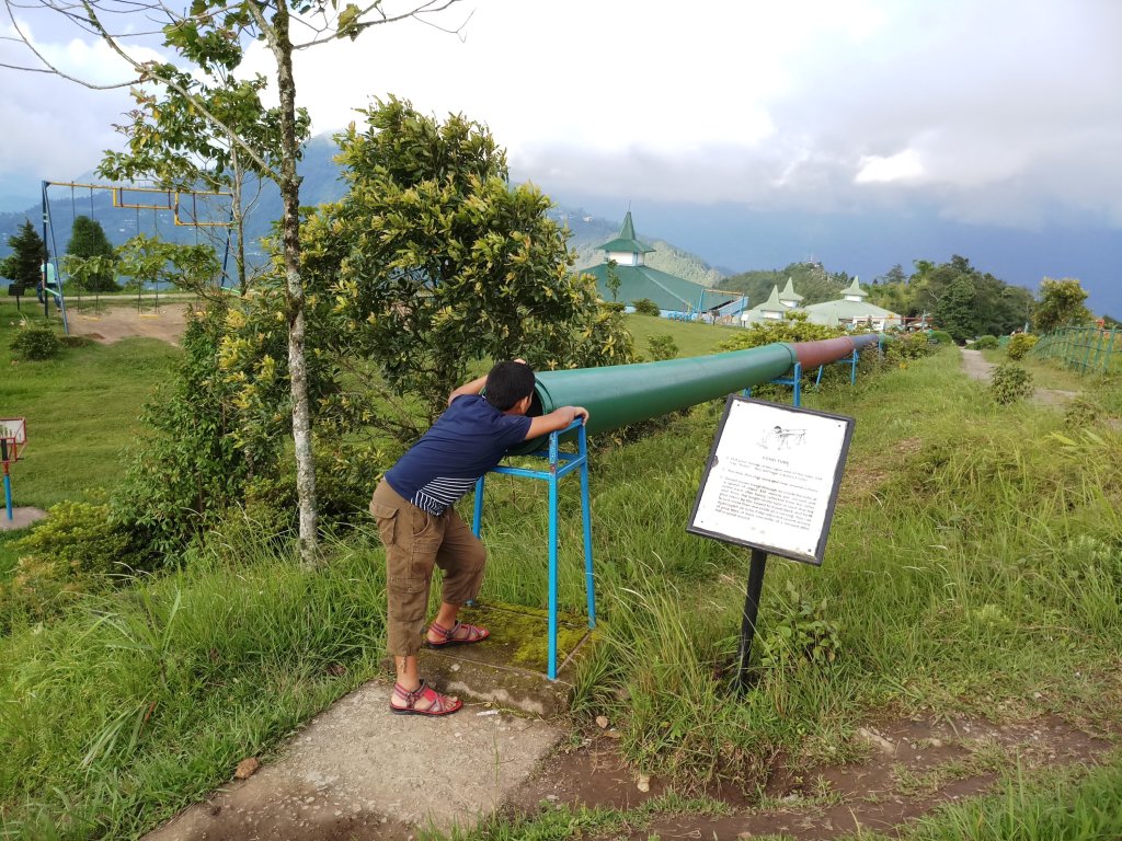 Kid looking through a long  cylindrical hollow pipe