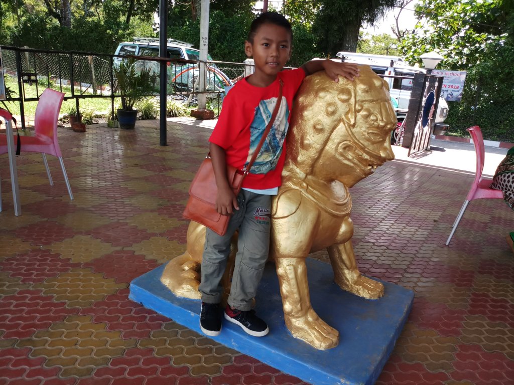 Kid with a golden statue of lion at Army Canteen in Army Golf Course kalimpong
